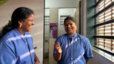 Two happy women outside a women's toilet.