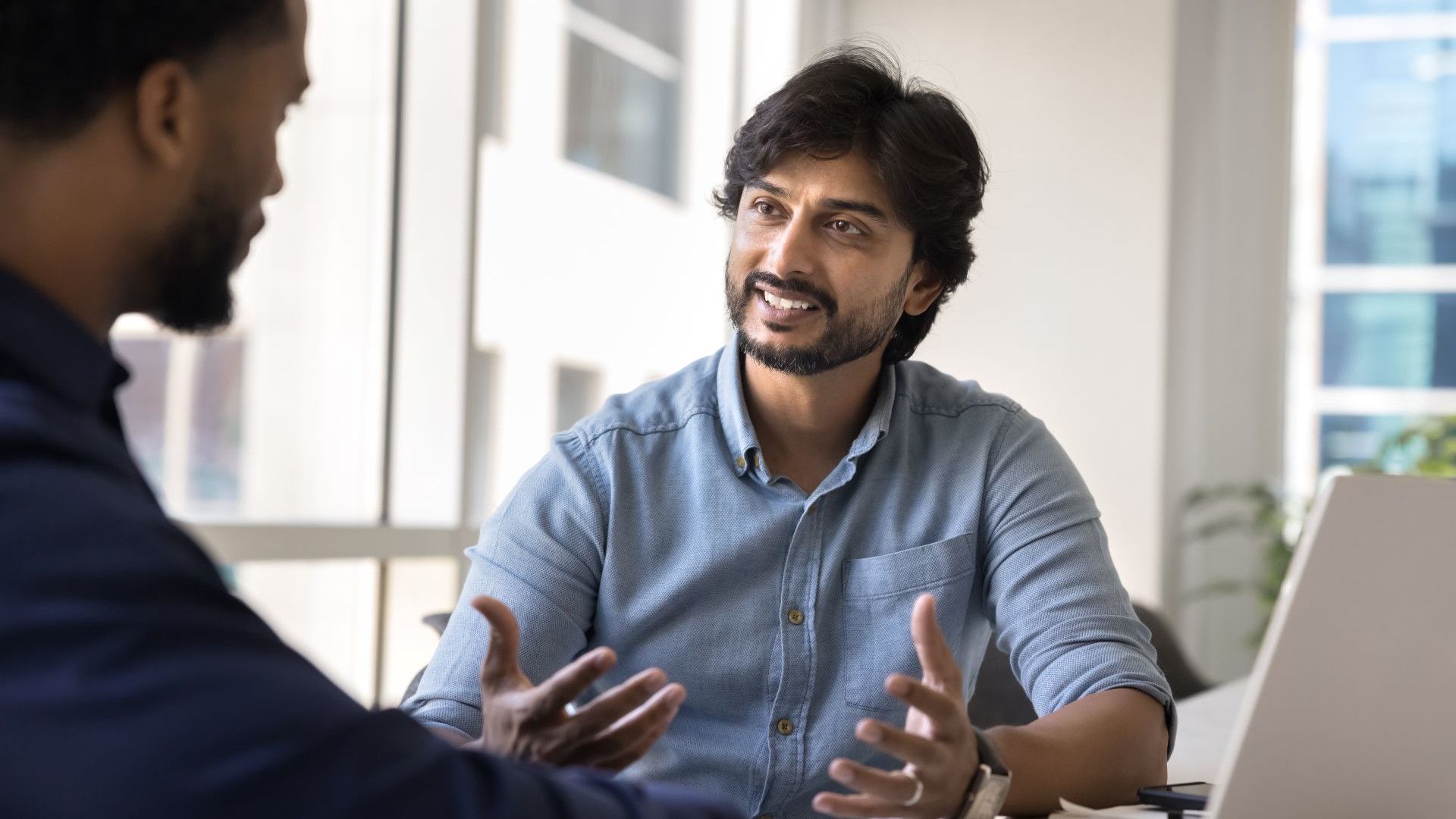 Two men engage in a conversation in a corporate setting.