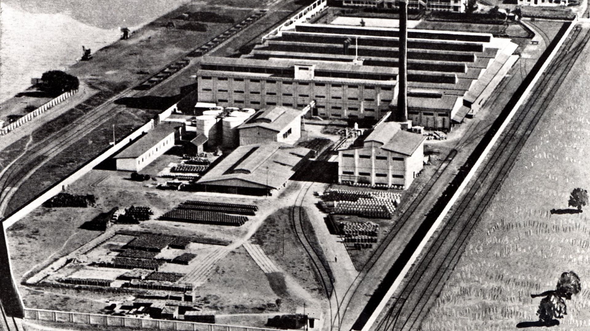 Historic aerial view of a large industrial factory complex beside railway tracks