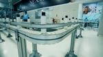White plastic bottles move along an automated conveyor line in a clean manufacturing facility.